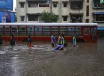 People wade through a water-logged road past a stalled passenger bus during rains in Mumbai, August 29, 2017.