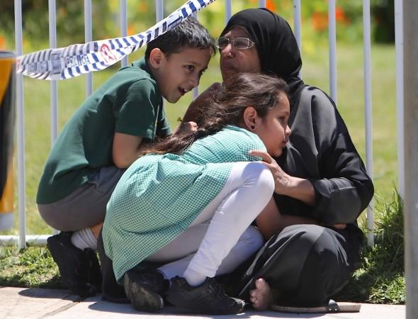 A woman hugs her children as she sits under police tape near where a vehicle crashed into a primary school classroom in the Sydney suburb of Greenacre in Australia, November 7, 2017. Sydney car crash