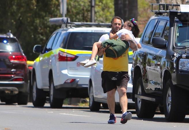 A man carries a child near where a vehicle crashed into a primary school classroom in the Sydney suburb of Greenacre in Australia, November 7, 2017. Sydney rescuer- car accident