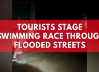 Tourists stage swimming race through flooded street
