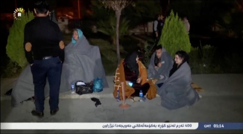 People sit on the pavement after an earthquake at an unknown location in Iraq in this still image taken from video November 13, 2017. Iran Iraq earthquake