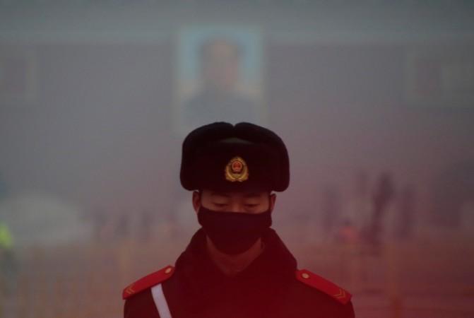 A paramilitary police officer wearing a mask stands guard in front of a portrait of the late Chairman Mao Zedong during smog at Tiananmen Square after a red alert was issued for heavy air pollution in Beijing, China, December 20, 2016. China pollution