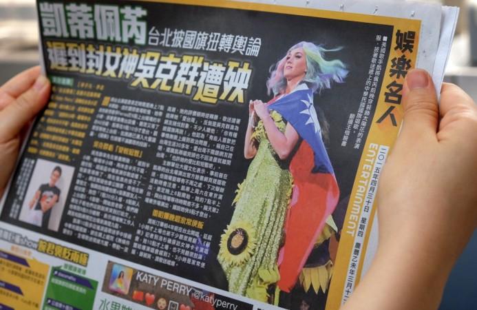 In this photo illustration taken on April 30, 2015, a local resident reads a newspaper showing US singer Katy Perry wearing Taiwan's national flag in Taipei. Katy Perry China controversy