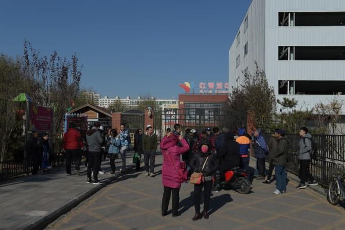 People stand in front of the main gate of the RYB Education New World kindergarten in Beijing on November 24, 2017. Beijing school