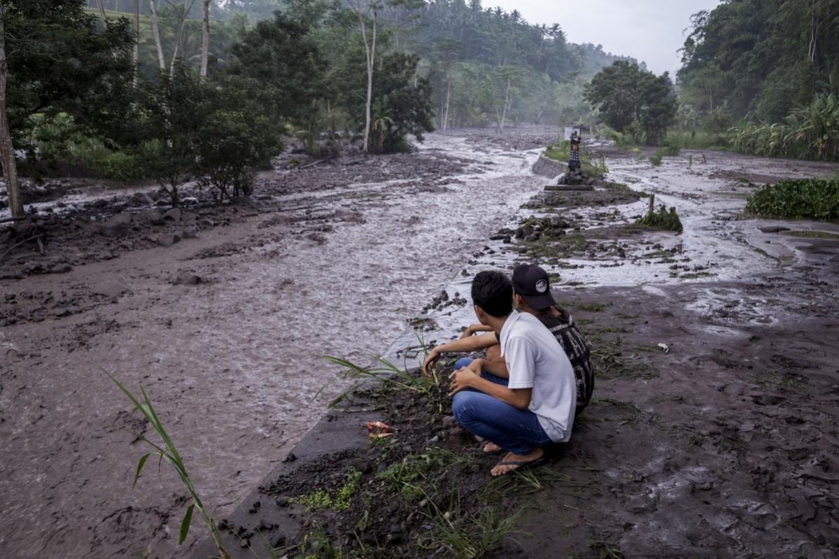 Volcanic material from Mount Agung flows through a local river in Gesing Village while villagers are seen watching nearby Bali volcano