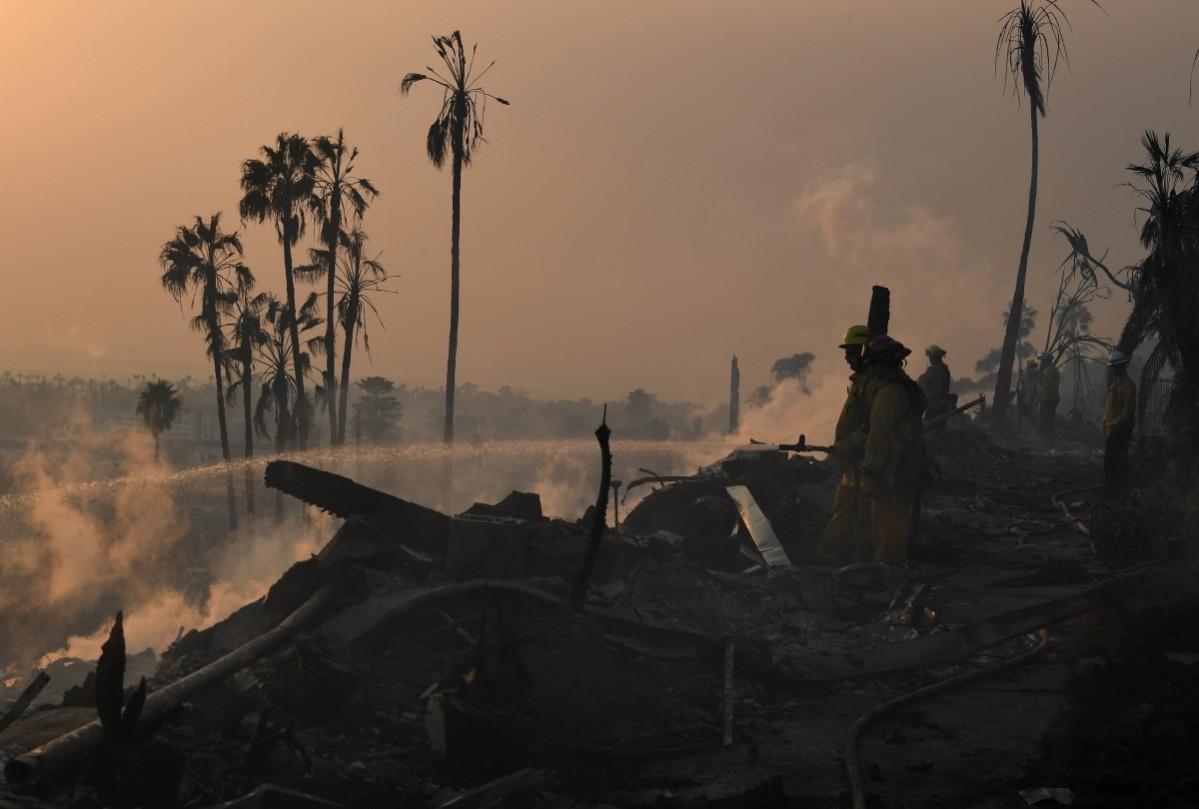 Firefighters hose down flareups at the two story Hawaiian Village Apartment complex that burnt to the ground during the Thomas wildfire in Ventura, California on December 5, 2017. California wildfire