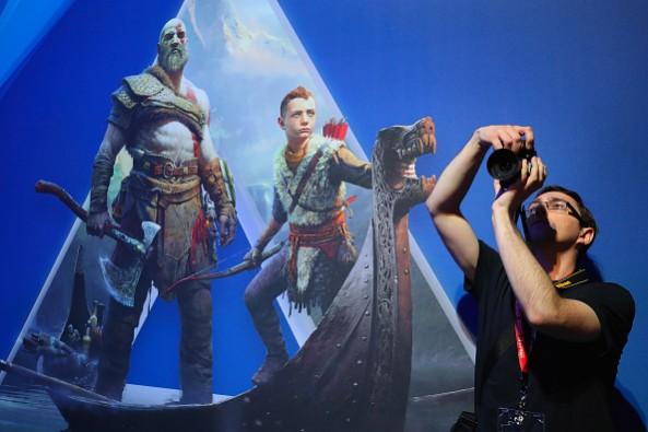LOS ANGELES, CA - JUNE 13: An attendee takes a photograph near an ad for 'God of War 4' during the Electronic Entertainment Expo E3 at the Los Angeles Convention Center on June 13, 2017 in Los Angeles, California. Annual E3 Gaming Industry Conference Held In Los Angeles