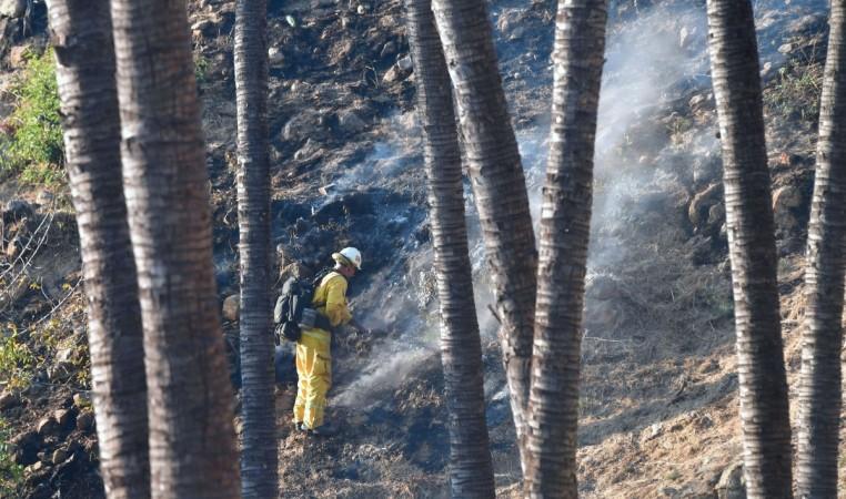A firefighter puts out burning embers on a hillside near homes in Bel Air California wildfire