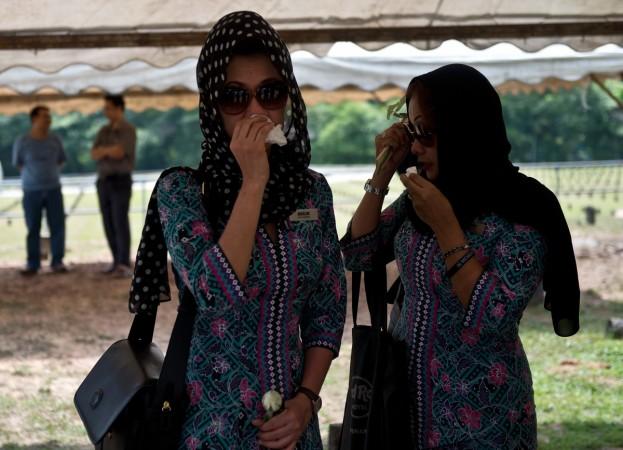 Colleagues of Malaysia Airlines MH17 chief stewardess Dora Shahila Kassim attend her burial ceremony in Kuala Lumpur on August 22, 2014. Millions of black-Clad Malaysians fell silent August 22 in tribute to their 43 countrymen killed in the MH17 disaster as the remains were brought home and laid to rest amid deep sorrow and anger. malaysia airlines