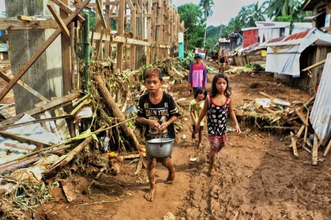 Children walk past debris and damaged houses trees in Barangay San Mateo Borongan in eastern Samar on December 17, 2017 Philippines