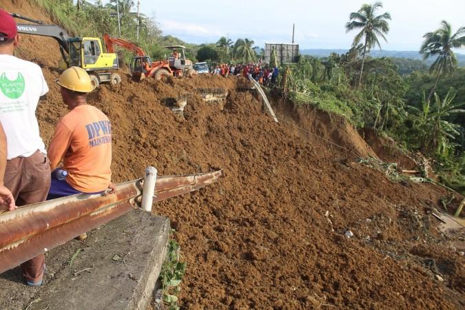 Philippines workers look on as bulldozers work on the edge of a collapsed highway after typhoon Kai-Tak in Pinabacdao town, western Samar province on December 17, 2017 Philippines