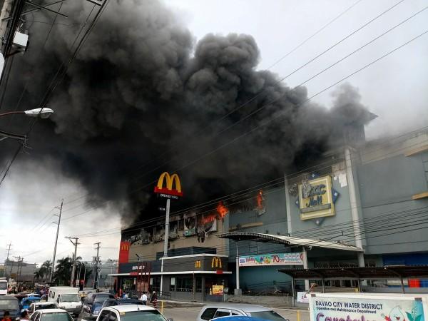 Smoke billows from a shopping mall on fire in Davao City, the Philippines, in this December 23, 2017 Philippines mall fire