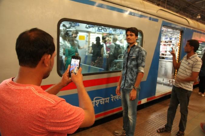 People click selfies in front of the first AC local of Mumbai on Monday, December 25, 2017. AC locals