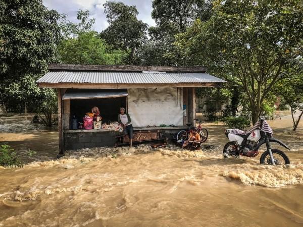 Residents wait in front of a store as it floods in Kabacan, North Cotabato, on the southern island of Mindanao on December 23 Philippines