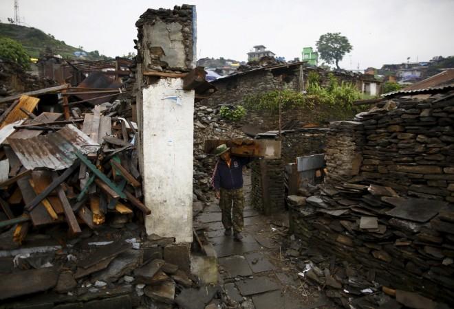 An earthquake victim, carrying wood recovered from a collapsed house, walks along a street near the debris of the collapsed houses at Barpak village at the epicenter of the April 25 earthquake in Gorkha district, Nepal, May 21, 2015. gorkha earthquake