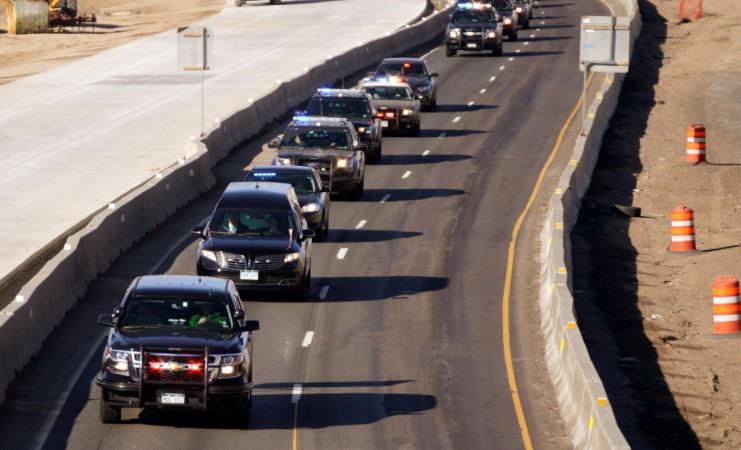A procession of police vehicles escorts the hearse carrying the body of a deputy killed in a domestic disturbance where multiple deputies and civilians were shot in Highlands Ranch, Colorado Colorado shooting