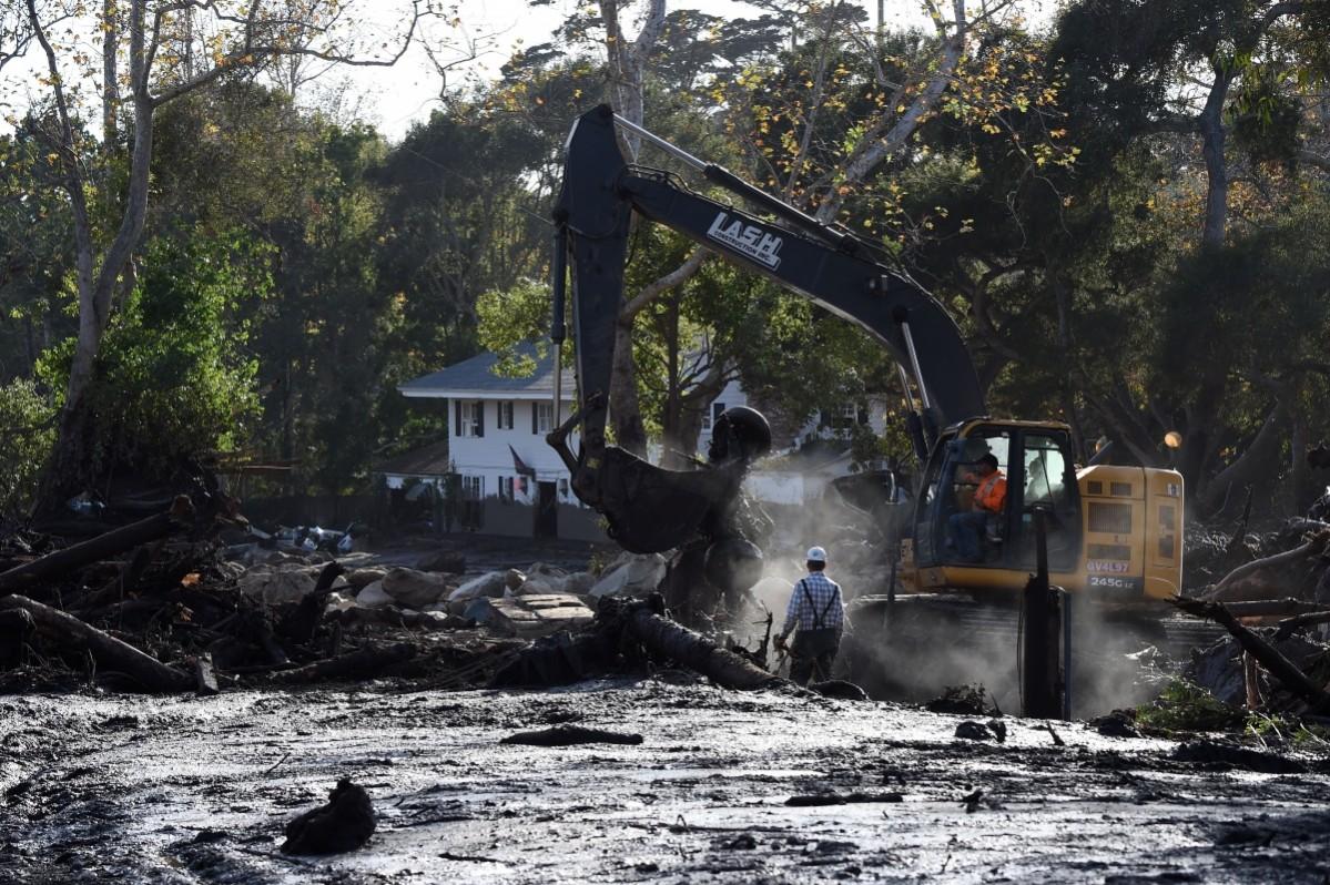 Workers use heavy machinery to clear mud and debris from an area where homes were destroyed by mudslides, in Montecito, California California mudslides