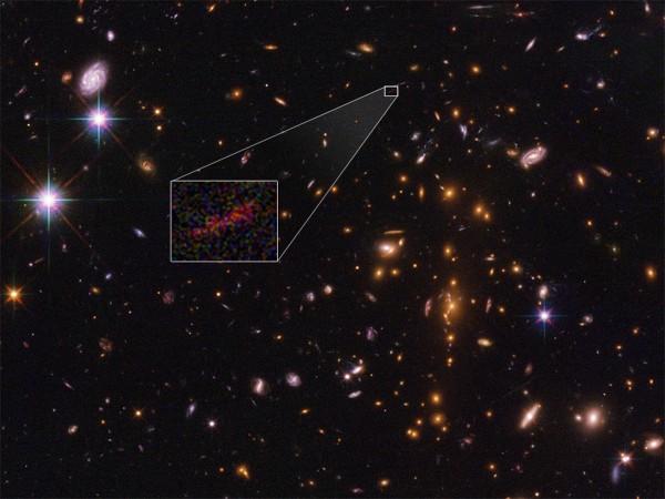 NASA's Hubble and Spitzer space telescopes captured the farthest galaxy yet seen in an image that has been stretched and amplified by a phenomenon called gravitational lensing. SPT0615-JD