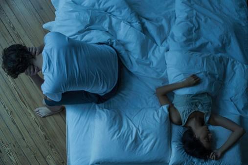 Man unable to sleep while wife sleeps comfortably unaware. Insomnia
