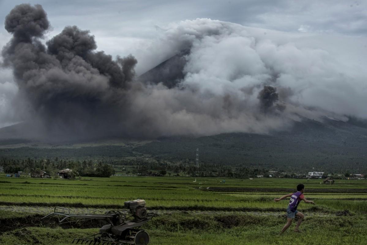 A boy runs as pyroclastic clouds emit from Mayon volcano on January 17, 2018 in Camalig, Philippines. Mount Mayon