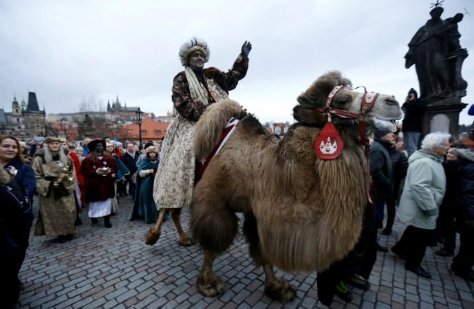 Men dressed as the Three Kings greet spectators as they ride camels during the Three Kings procession across the medieval Charles Bridge, as a part of a re-enactment of the Nativity scene, in Prague, Czech Republic January 5, 2018. King Abdulaziz Camel Festival