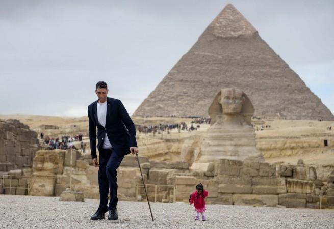 India's Jyoti Amge (R), the world's shortest woman poses for a picture with Sultan Kosen of Turkey, the world's tallest man, at the site of the Pyramids of Giza in Egypt on January 26, 2018, with the Sphinx and the Pyramid of Khafre (also known as Chephren) seen in the background. world's smallest woman and world's tallest man