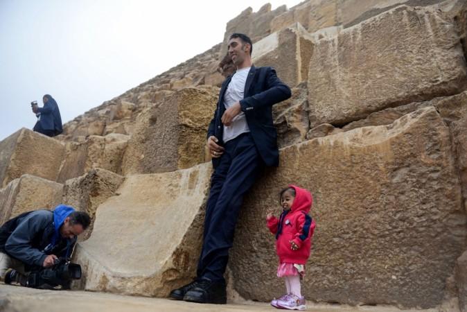 India's Jyoti Amge (R), the world's shortest woman poses for a picture with Sultan Kosen (C) of Turkey, the world's tallest man, at the foot of one of the three Pyramids of Giza in Egypt on January 26, 2018. world's smallest woman and world's tallest man