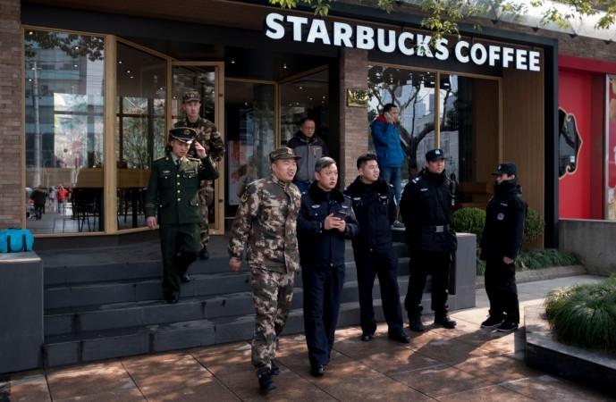 Police officers stand in front of a Starbucks in Shanghai on February 2, 2018, after a van caught fire and ploughed into pedestrians China accident