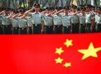 Retiring paramilitary policemen take their oaths in front of a Chinese national flag