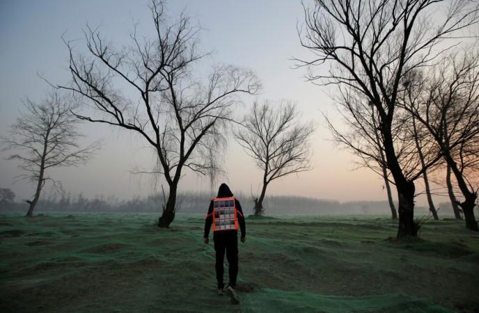 Artist Liu Bolin wearing a vest with 24 mobile phones walks in smog. Beijing pollution