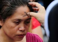 A Catholic nun marks a cross on the forehead of a devotee using ash during the observance of Ash Wednesday