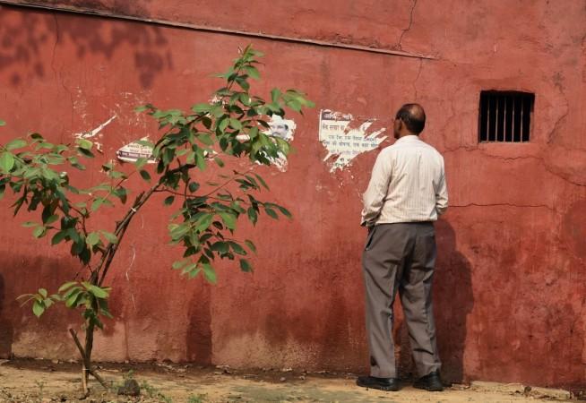 man urinates against a wall