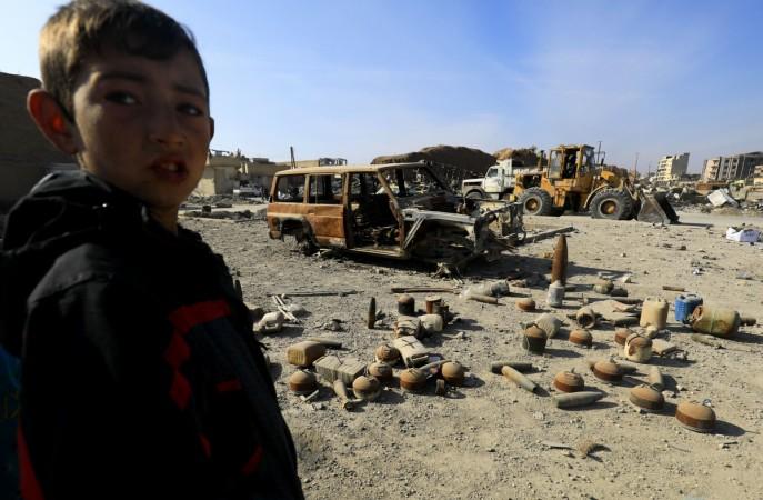 A Syrian boy stands near shells and undetonated mines lying on a street in Raqa that were left by the Islamic State (IS) group on January 16, 2018. ISIS children