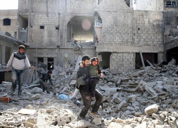 A man carries an injured boy as he walks on the rubble of damaged buildings in the rebel-held besieged town of Hamouriyeh, eastern Ghouta. syria