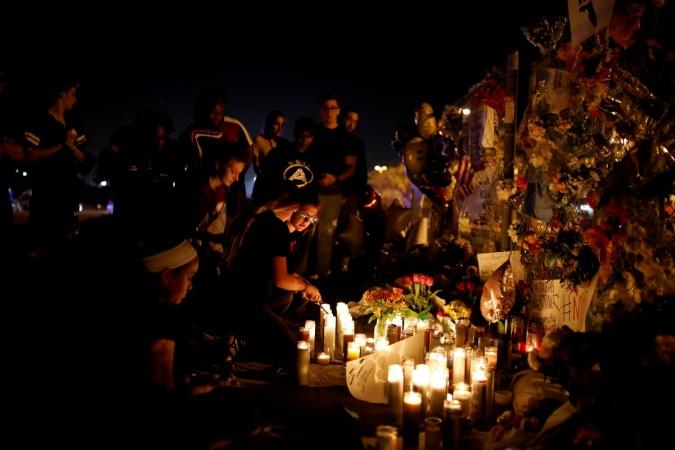 People light candles in front of mementos placed in front of the fence of the Marjory Stoneman Douglas High School to commemorate the victims of the mass shooting. florida shooting