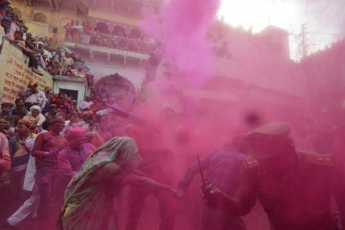 Coloured powder is thrown over Indian villagers during the Lathmar Holi celebrations in the village of Barsana on the outskirts of Mathura in the northern Indian state of Uttar Pradesh on February 24, 2018. Lathmar Holi in Uttar Pradesh