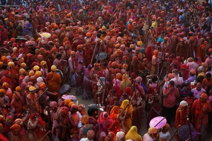 Men shield themselves from women playfully beating them with bamboo sticks during Lathmar Holi in Uttar Pradesh