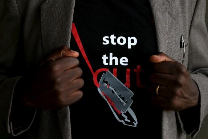 A man shows the logo of a T-shirt that reads female genital mutilation