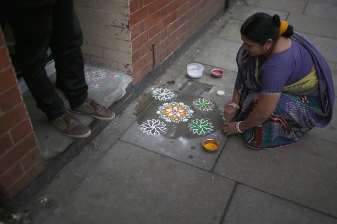 A woman decorates the pavement outside her home Rangoli