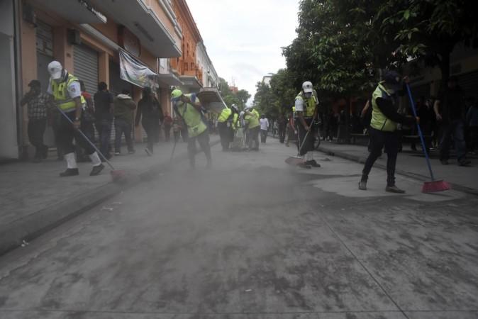 Municipal employees sweep up ash after the eruption of the Fuego Volcano, in Guatemala City, on June 3, 2018 Guatemala volcano