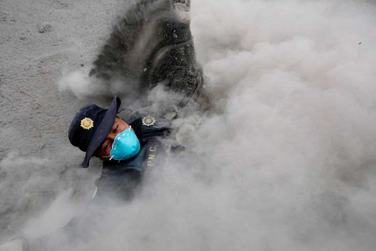 A police officer stumbles while running away from a new pyroclastic flow spewed by the Fuego volcano in the community of San Miguel Los Lotes in Escuintla, Guatemala, June 4, 2018. Guatemala volcano