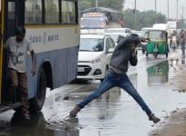An Indian pedestrian jumps a puddle of water as he crosses the road after copious rains in Bangalore