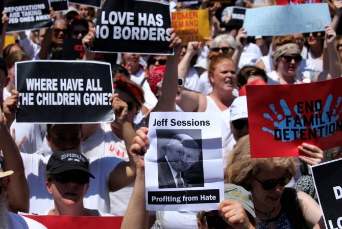 A demonstrator holds an image of U.S. Attorney General Jeff Sessions as hundreds of women and immigration activists march as part of a rally calling for US immigration crackdown