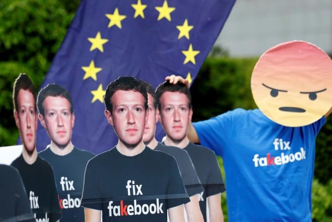A protester holds an European Union flag next to cardboard cutouts depicting Facebook CEO Mark Zuckerberg during a demonstration ahead of a meeting between Zuckerberg and leaders of the European Parliament in Brussels, Belgium May 22, 2018. Trouble for Facebook