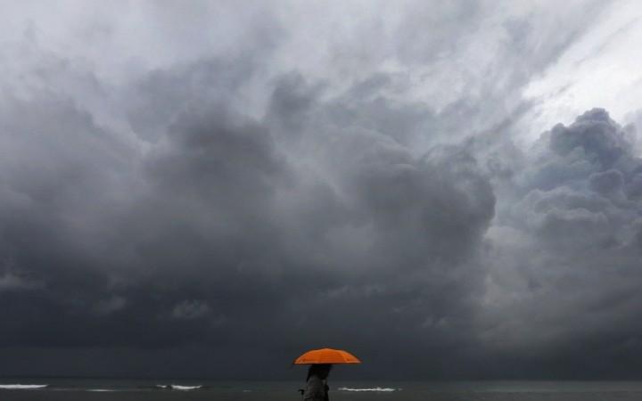 A woman holds an umbrella as heads to a railway station after work during a rainy day in Colombo October 17, 2014. A woman walks alone by the beach