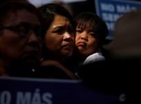 A child embraces a woman as people protest against Trump