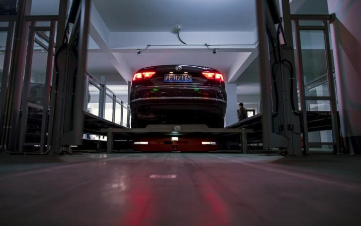 This picture taken on November 25, 2016 shows people watching a robotic unit of the smart parking system developed by Hikvision in a garage in Wuzhen Township of Tongxiang City, in east China's Zhejiang province. Robotic car parking