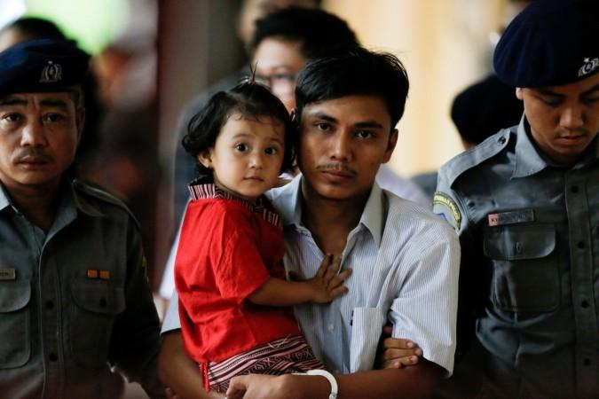 Detained Reuters journalist Kyaw Soe Oo carries his daughter Moe Thin Wai Zin while escorted by police during a court hearing in Yangon, Myanmar, June 5, 2018. Detained Reuters journalist Kyaw Soe Oo