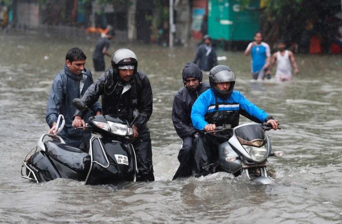 A man pushes his scooter as another rides his motorcycle through a waterlogged street during heavy rains in Mumbai Mumbai rain