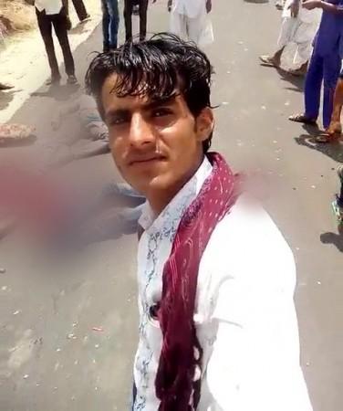 This man with a red scarf around his neck is being condemned for taking a selfie with victims and not helping them. rajasthan road accident